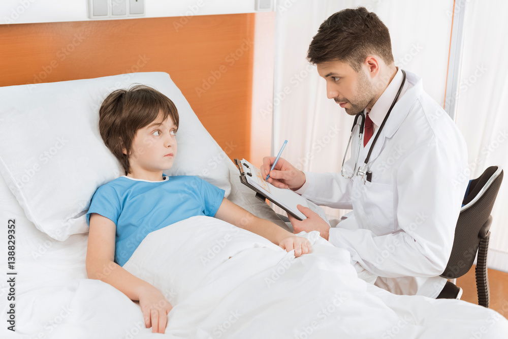 Obraz premium doctor writing down child patient's symptoms in hospital