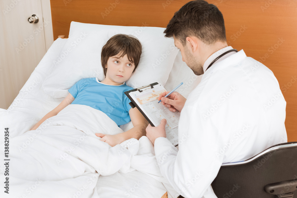 Fototapeta premium doctor writing down child patient's symptoms in hospital