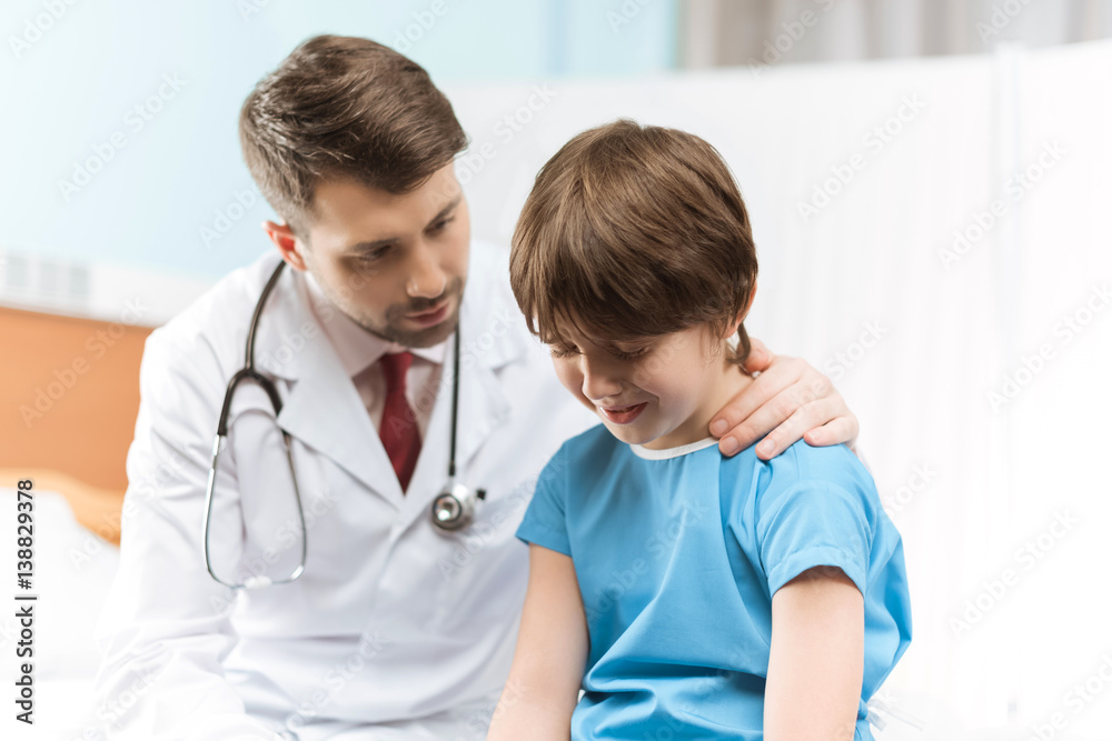 portrait of doctor cheering up little crying boy in hospital portrait of doctor cheering up little crying boy in hospital