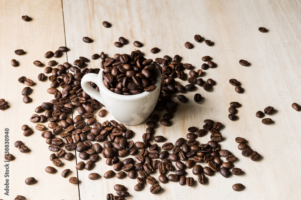 Cup full of coffee beans on wood background Cup full of coffee beans on wood background