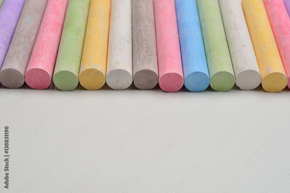 Pieces of chalks in a variety of colors arranged in line on a white background. Back to school,education, arts, creative. Image with room for text