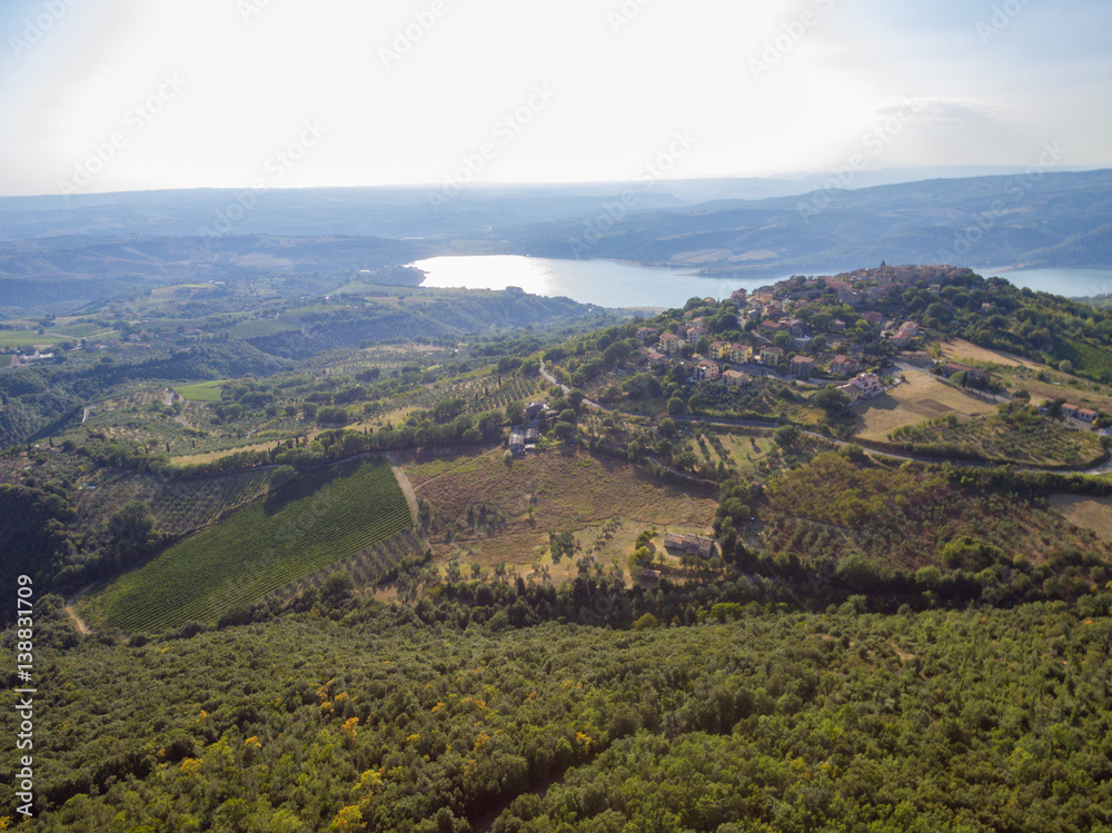 Aerial photo of a small italian village on a hill next to a lake 