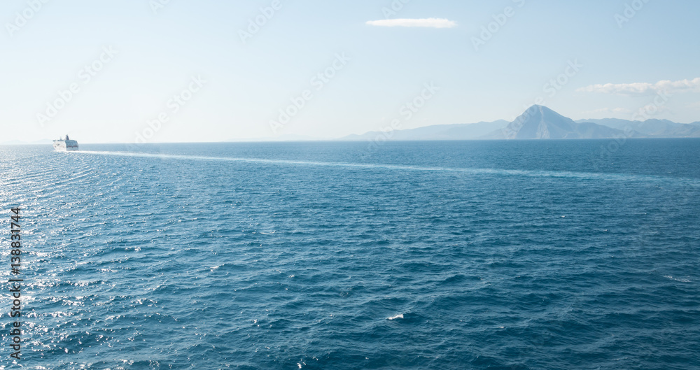 Cruise ship on the mediterranean sea near the horizon with a mountain in the background 