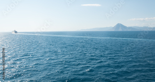 Cruise ship on the mediterranean sea near the horizon with a mountain in the background 