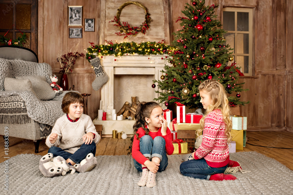 kids sitting on carpet with Christmas gifts