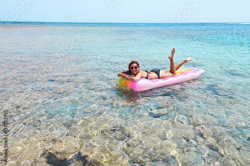 Happy young woman lying on pool raft at seaside © Olesya Shelomova