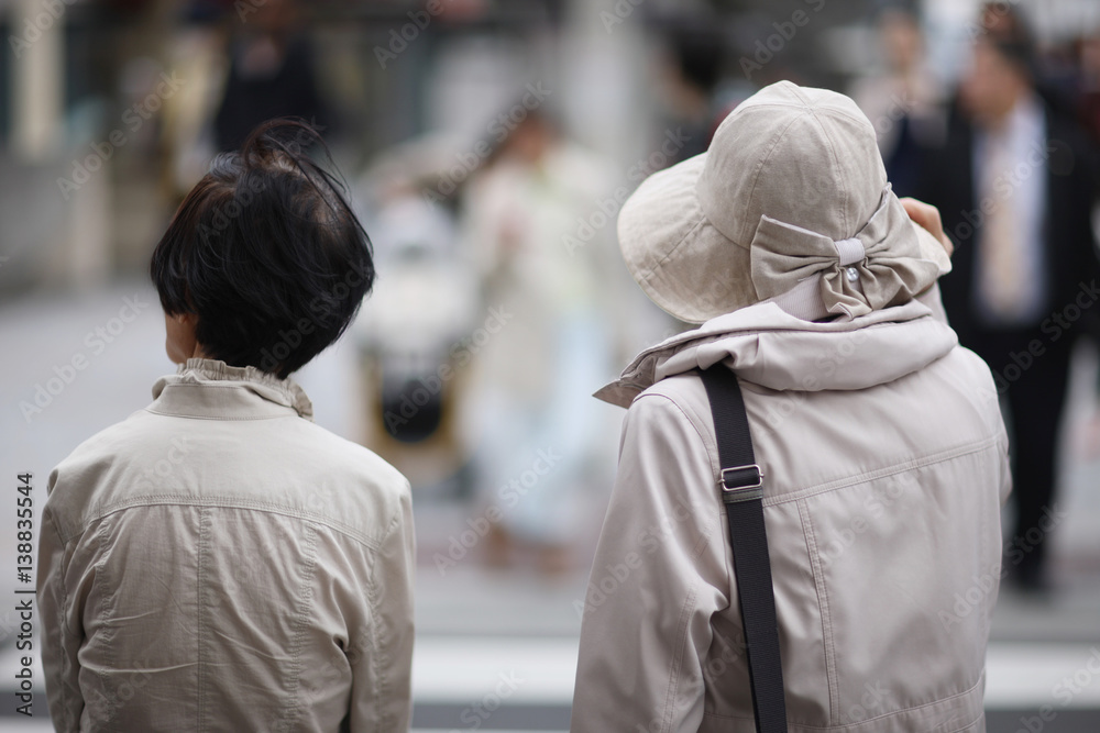 Two women at a crosswalk on a street in Tokyo, Japan.