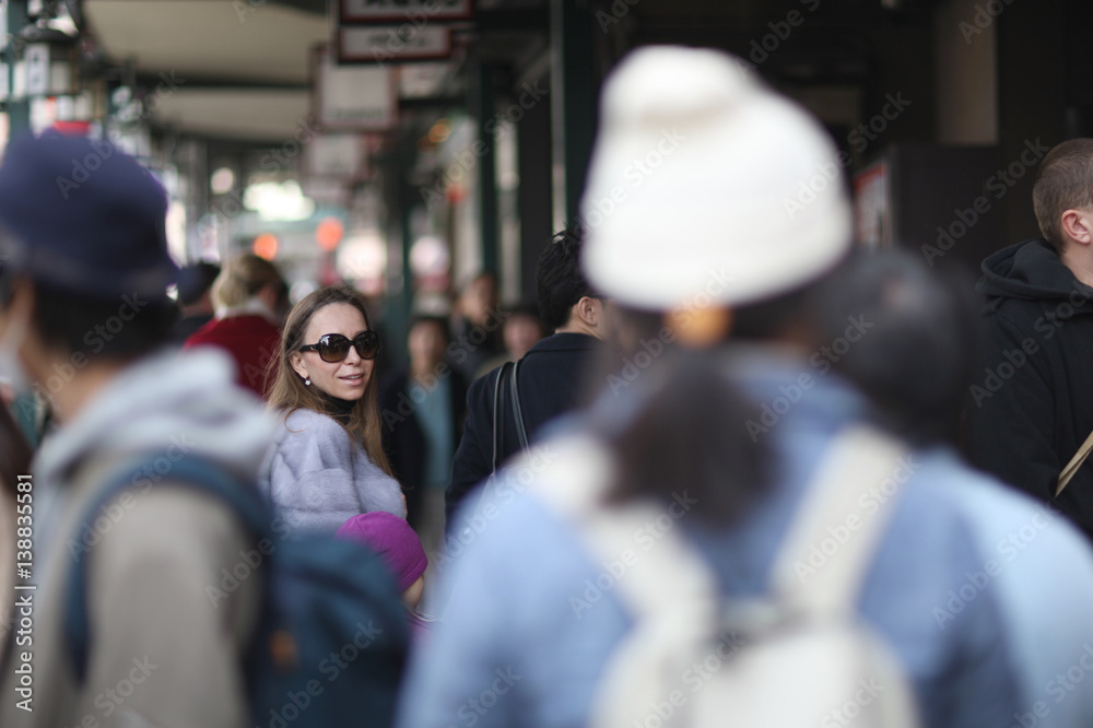 The woman's face wearing sunglasses in the crowd of passers on the streets of Tokyo, Japan.