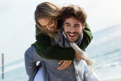 Happy young couple enjoying the day in a cold winter on the beach.