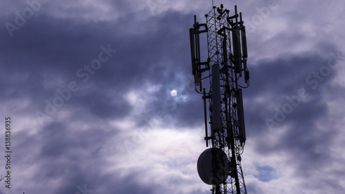 Telecommunication tower with clouds and sun in background