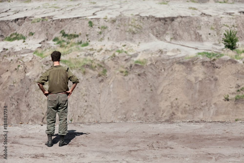 Soldier in green uniform standing in desert during military training Soldier in green uniform standing in desert during military training