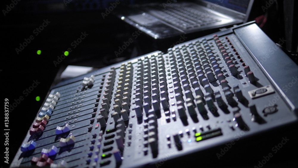Soundman's palm and microphone on sound mixer background. Music instruments or dj concept. Musical equipment microphone with control console.