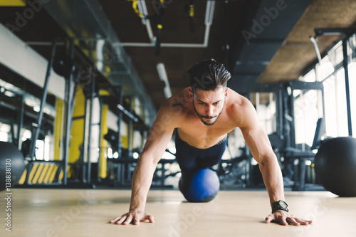 Fototapeta Naklejka Na Ścianę i Meble -  Sporty athlete doing push ups in gym