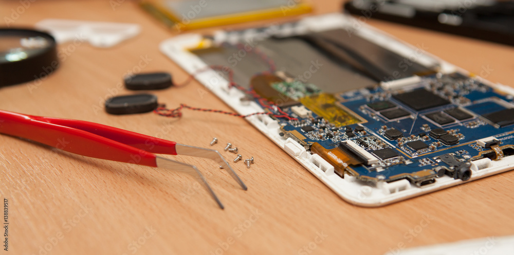 Disassembled computer tablet on wooden background. Disassembled computer tablet on wooden background.