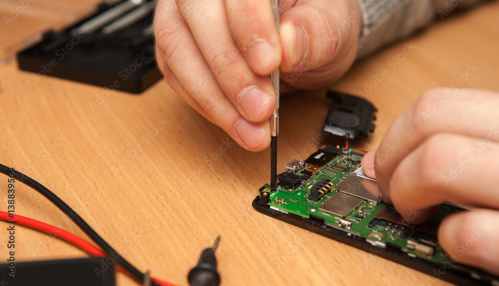 technician to disassemble the smartphone. Hands close-up.