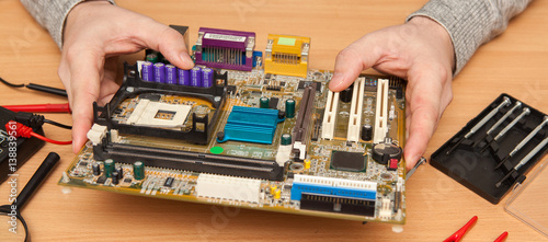 Technician holding the motherboard in the hands. Maintenance in the workshop.