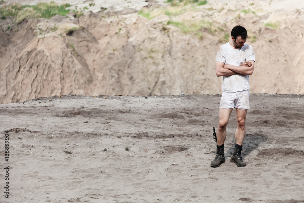 Man in white t-shirt standing with crossed arms in desert Man in white t-shirt standing with crossed arms in desert