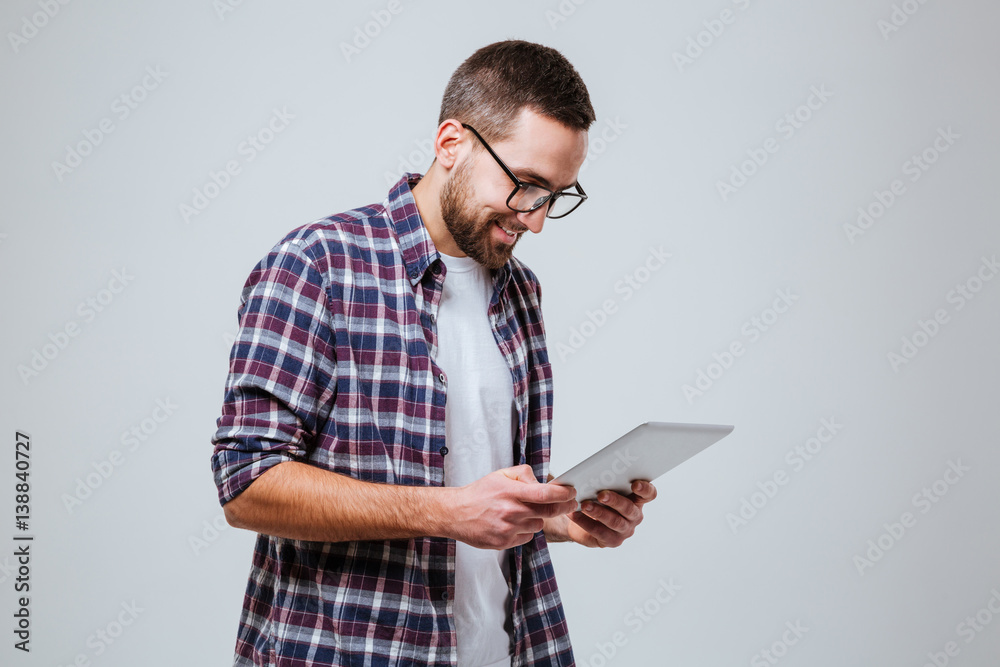Smiling Bearded man in eyeglases using tablet computer Smiling Bearded man in eyeglases using tablet computer