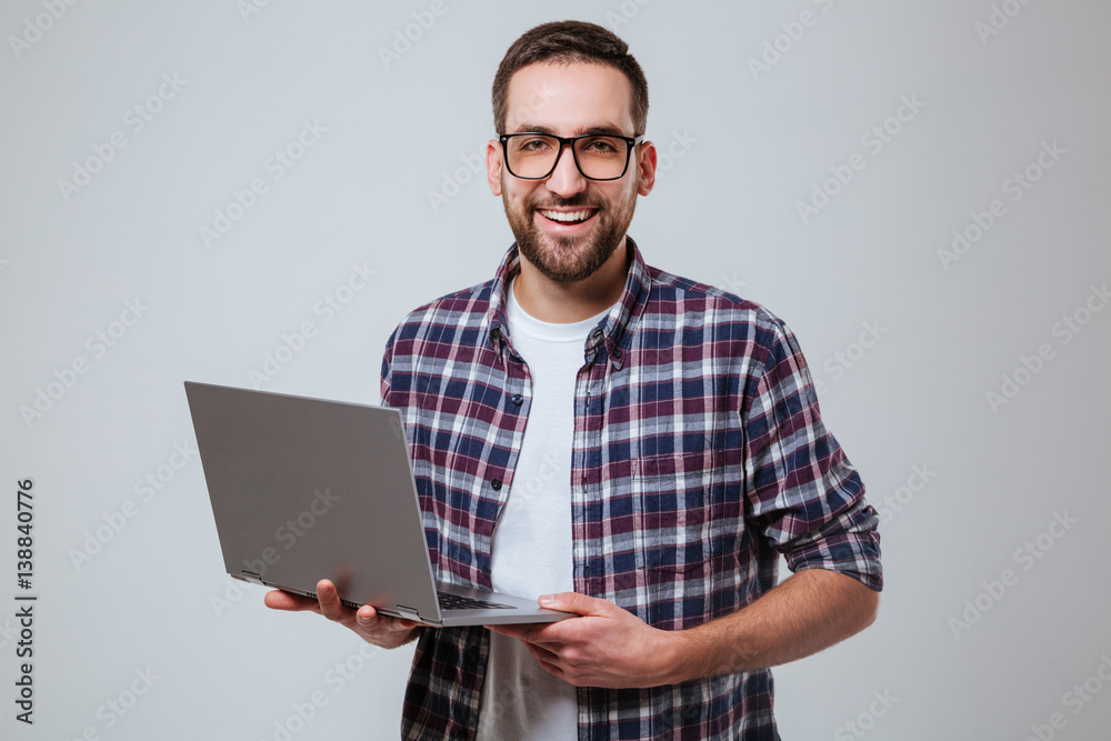 Smiling Bearded man in eyeglases holding laptop Smiling Bearded man in eyeglases holding laptop