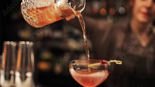 barmaid with glass and jug preparing cocktail