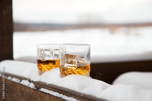 Two whiskey glasses in the snow on a winter background. photo