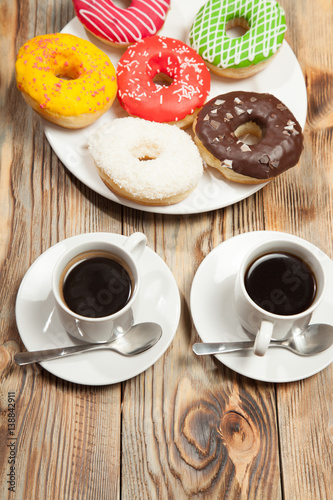 Two cups with coffee and donuts on a wooden background