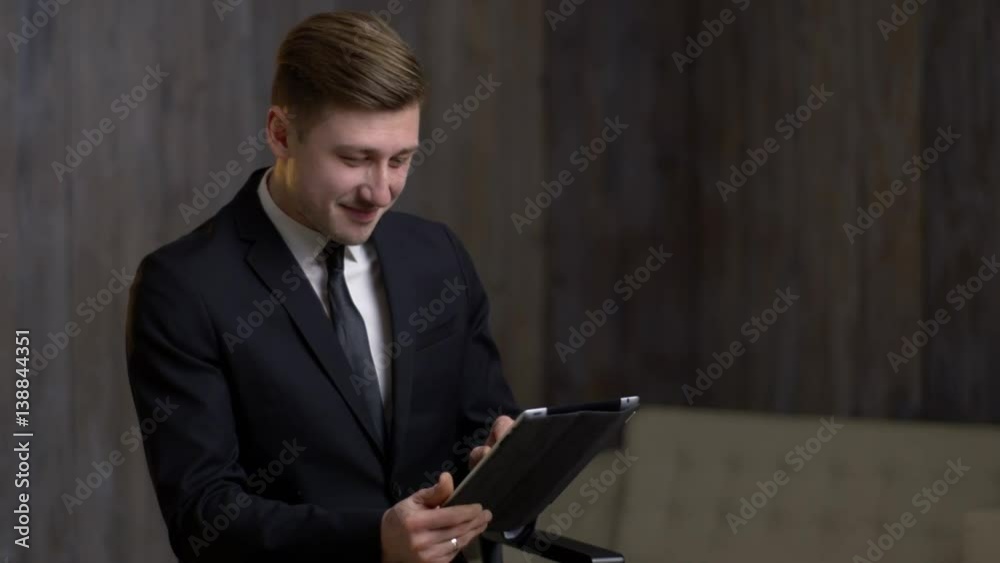 young businessman with a tablet computer is engaged in business. A man is in a building with a modern interior. he laughs young businessman with a tablet computer is engaged in business. A man is in a building with a modern interior. he laughs
