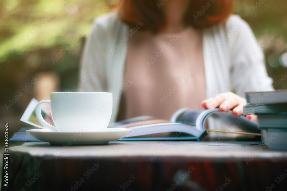 Woman is reading a book and drinking coffee in the garden. Woman is reading a book and drinking coffee in the garden.