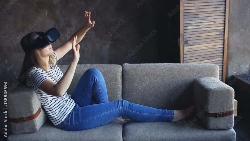 young woman sitting on sofa at living room and using VR headset