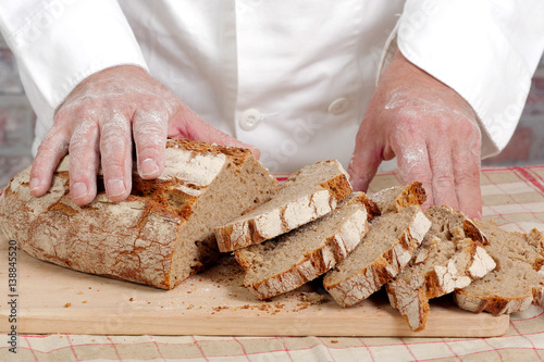 Baker hands with fresh bread on wood table