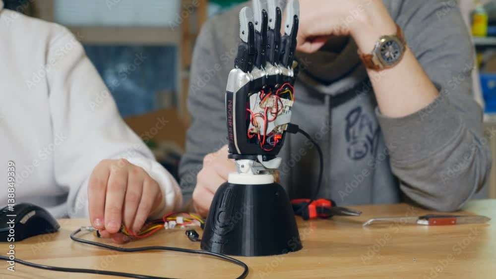 Creative engineers team at modern start up office working with innovative bionic robotic arm. Dolly camera movement. 4K.
