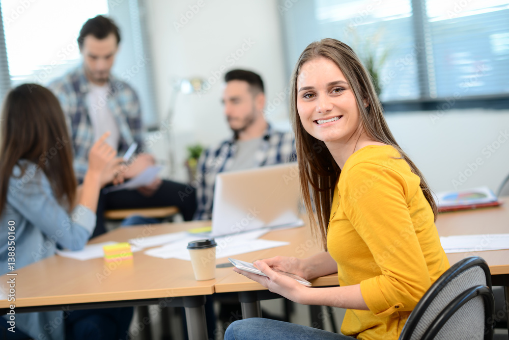 portrait of young woman in casual wear working in a creative business startup company office with coworker people in background