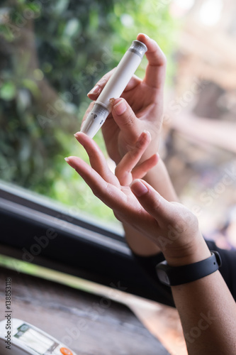 Close up of asian woman hands using lancet on finger to check blood sugar level by glucose meter, Healthcare medical and check up, diabetes, glycemia, and people concept