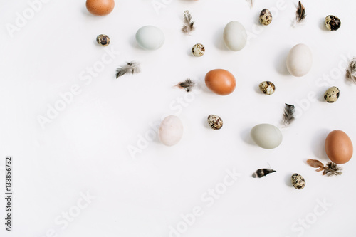 White and brown Easter eggs, quail eggs and feathers on white background. Flat lay, top view. Traditional spring concept.