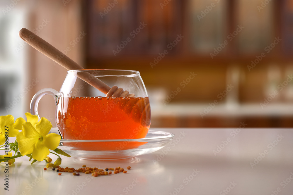 Glass jar with honey and dipper on white kitchen table Glass jar with honey and dipper on white kitchen table