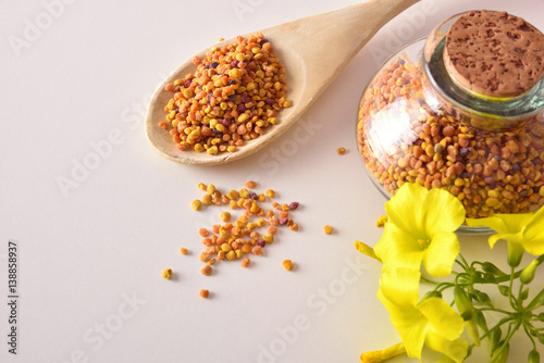 Grains of bee pollen in jar and wooden spoon top