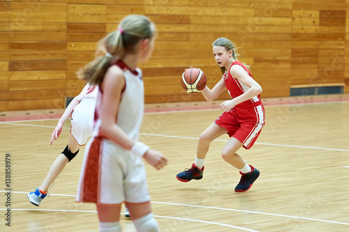 Girls in sport uniform playing basketball indoors