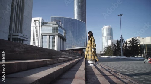 Stylish female climbing up the city stairs