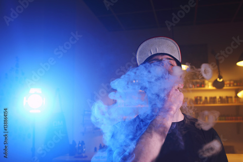 Vaping man in a cloud of vapor in a vape bar. close-up. photo