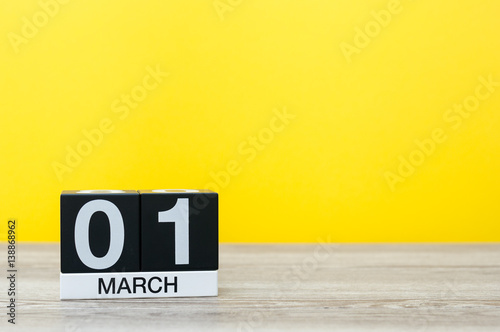 March 1st. Day 1 of month, calendar on table with yellow background. Spring time, empty space for text