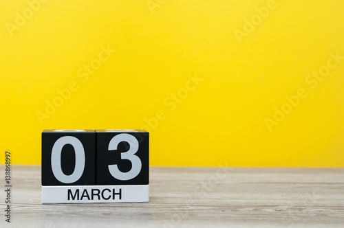 March 3rd. Day 3 of month, calendar on table with yellow background. Spring time, empty space for text