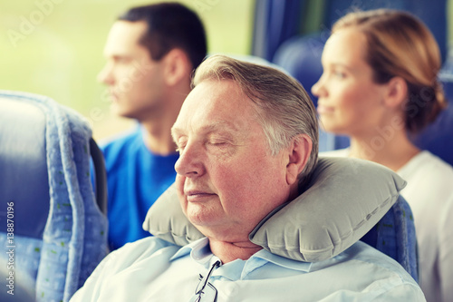 senior man sleeping in travel bus with neck pillow