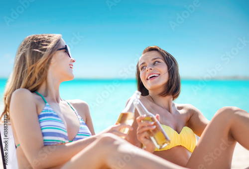 happy young women with drinks sunbathing on beach © Syda Productions