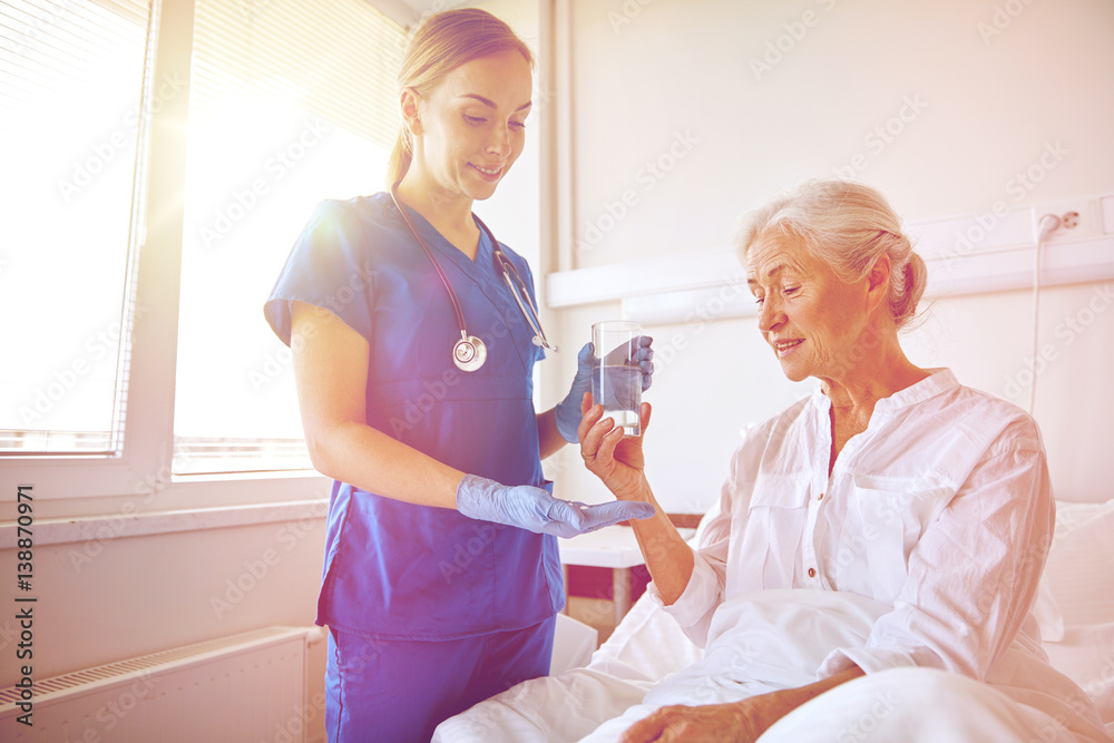 Obraz premium nurse giving medicine to senior woman at hospital