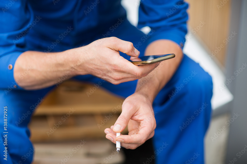 auto mechanic smoking cigarette at car workshop