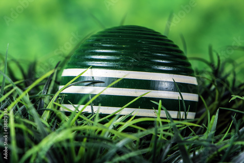 green striped wooden croquet ball in green grass with green background photo