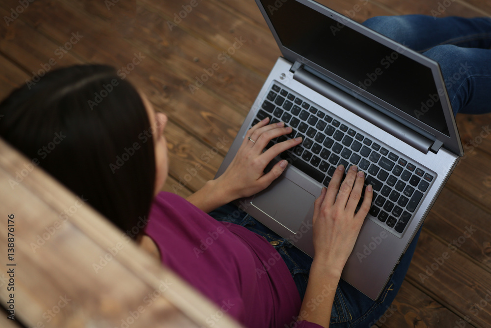 Student woman hold a laptop on her knees sitting on the floor and learn, with depth of field image Student woman hold a laptop on her knees sitting on the floor and learn, with depth of field image