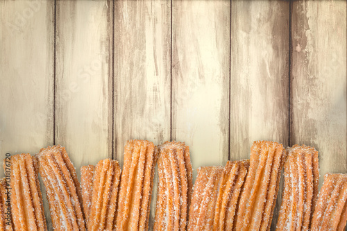Churros arranged in row on wooden background