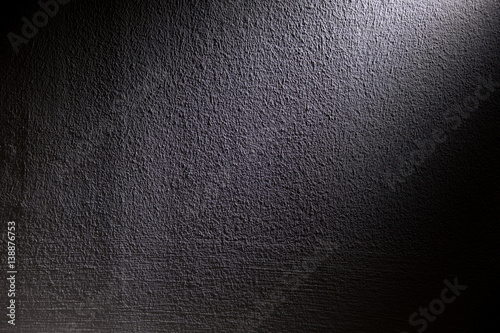 White, blur spotlight effect on black background. Concrete wall.