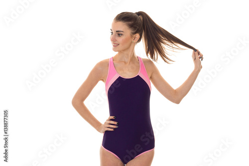 beautiful slim young girl in body swimsuit turned her head to the side and keeps a hand on the hip © ponomarencko